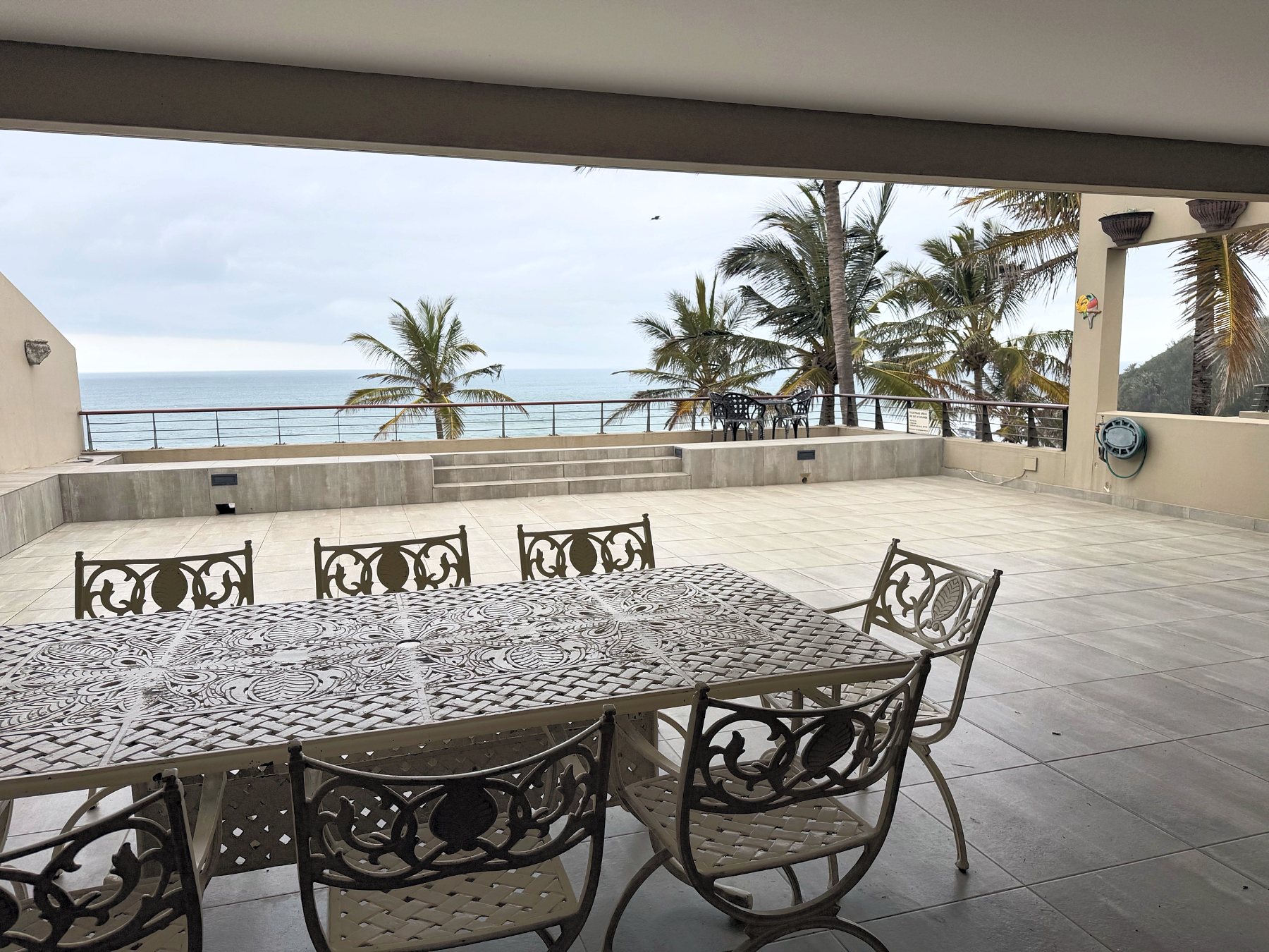 Raised balcony with dining table looking out over palms to the sea